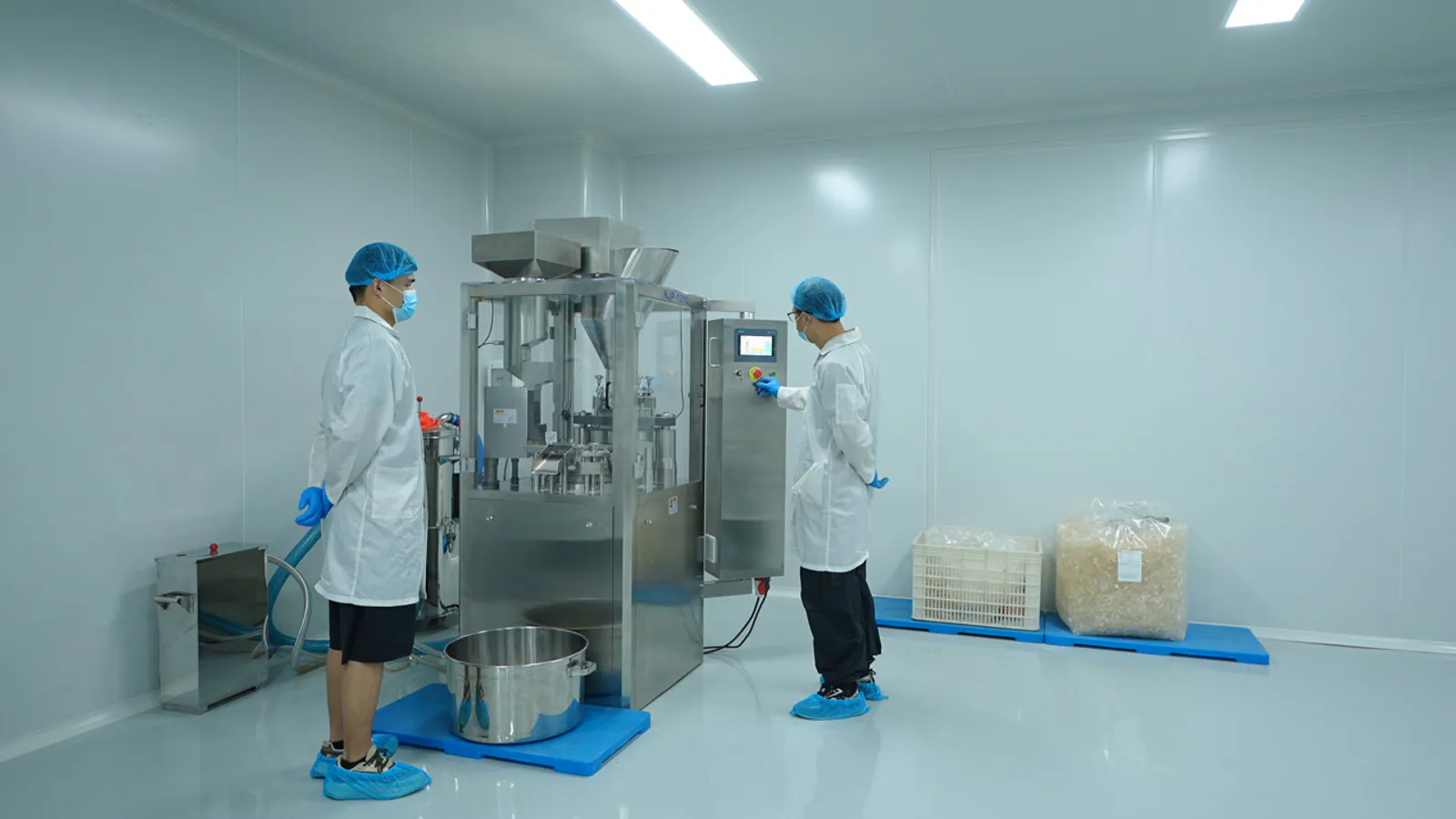 工作人员配合操作营养补充剂生产设备